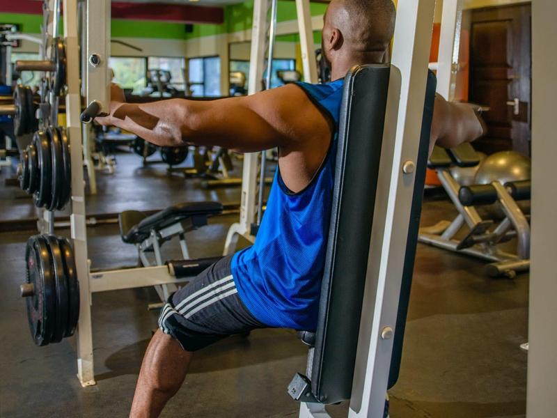 Homme s'entraîne aux épaules sur une machine dans une salle de sport d'hôtel.
