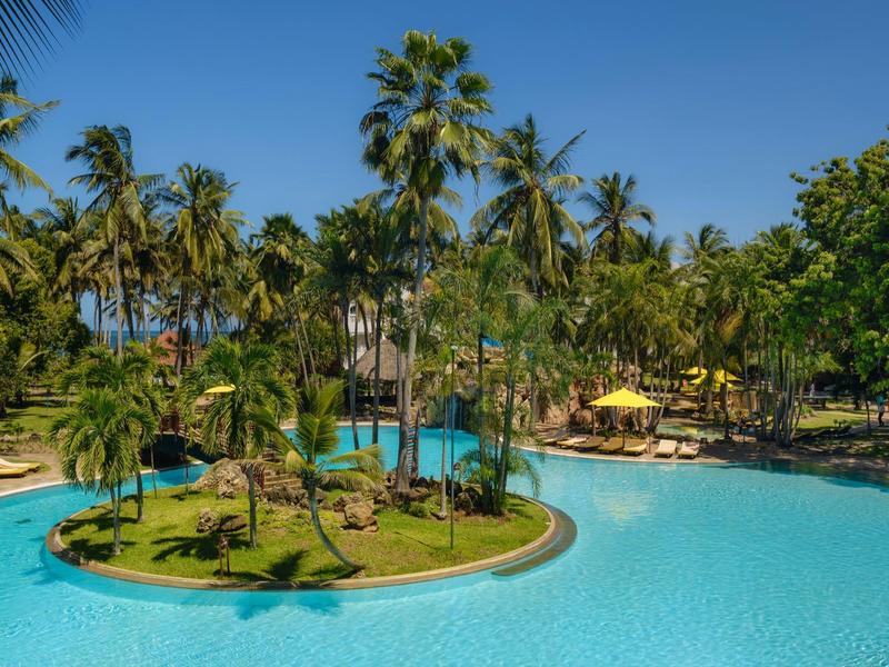 Deux chaises et une table dressée sur la plage au coucher du soleil.
