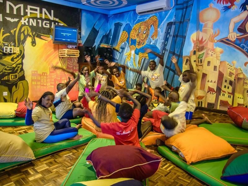 Espace enfant coloré et ludique avec coussins et fresques murales dans un hôtel.