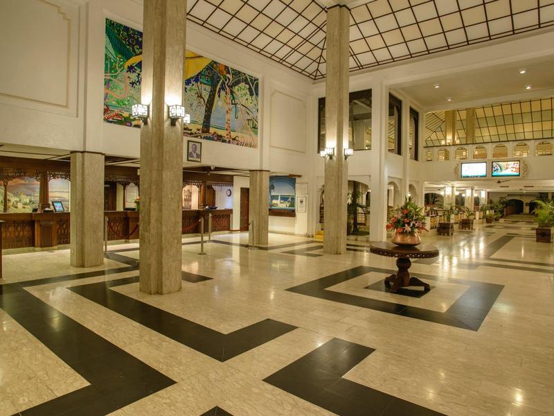 Grand hall d'hôtel avec sol en marbre, colonnes hautes et espaces lounge.