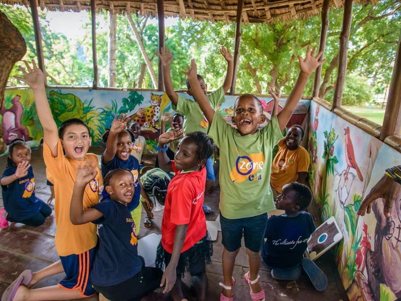 Enfants joyeux en vêtements colorés dans un espace extérieur couvert lors d'une activité de vacances.