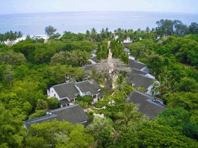 Resort con più edifici circondati da vegetazione tropicale fitta vicino al mare.