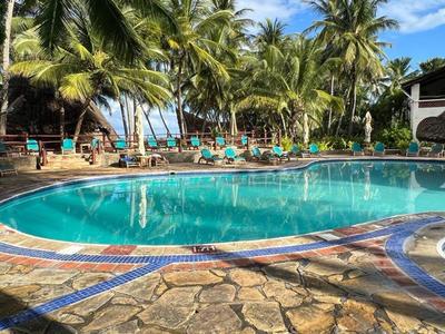 Piscine d'hôtel avec palmiers et chaises longues sous un ciel clair