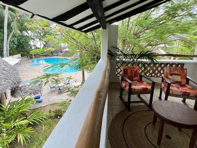 Balcone con posti a sedere con vista piscina e palme in hotel tropicale