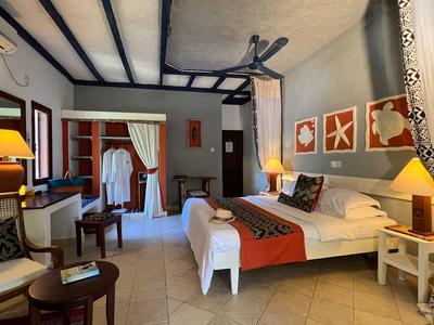 Elegante camera d'hotel con letto grande, zona salotto e illuminazione calda.