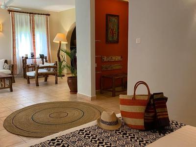 Camera d'hotel accogliente con due poltrone, un tappeto e ingresso con borse di vimini.