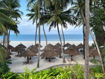 Spiaggia con palme, tetti di paglia e vista sul mare con cielo sereno