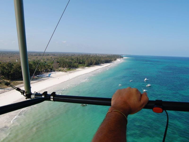 Vista di una lunga spiaggia di sabbia bianca e mare turchese da un parapendio.