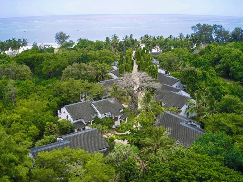 Resort con più edifici circondati da vegetazione tropicale fitta vicino al mare.