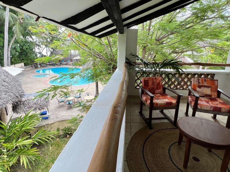 Balcone con posti a sedere con vista piscina e palme in hotel tropicale