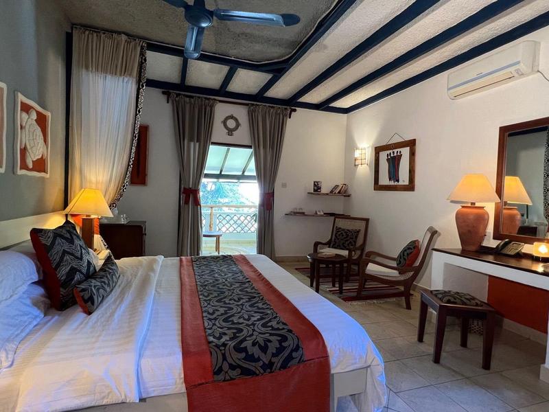 Camera d'hotel accogliente con travi in legno, letto, scrivania e luce calda.