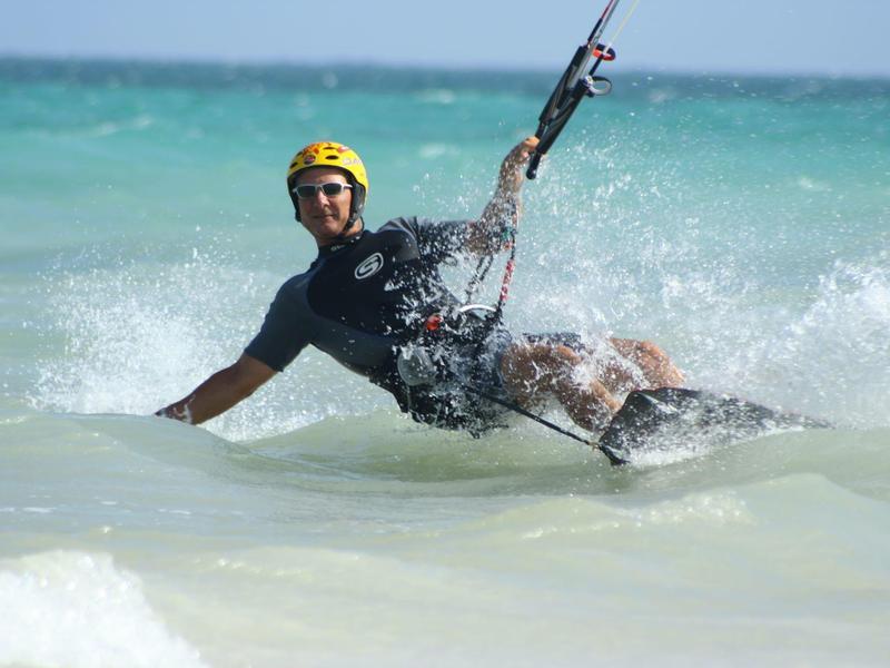 Uomo con casco giallo che fa kitesurf sulle onde dell'oceano.