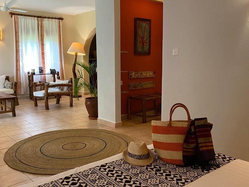 Camera d'hotel accogliente con due poltrone, un tappeto e ingresso con borse di vimini.