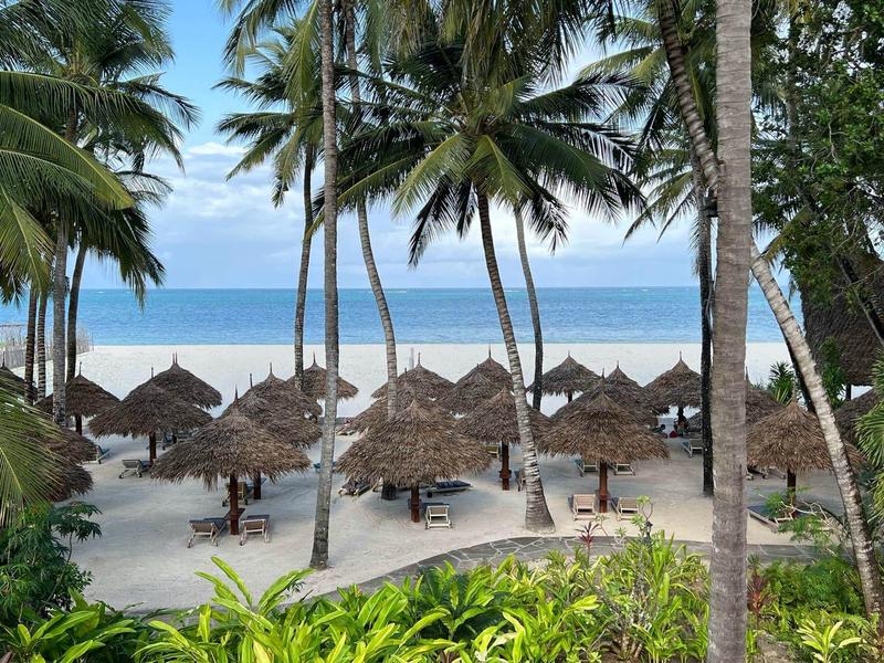 Spiaggia con palme, tetti di paglia e vista sul mare con cielo sereno