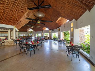 Großer Hotel-Speisesaal mit Holzdach, vielen Tischen und Stühlen und natürlichem Licht durch Fenster.