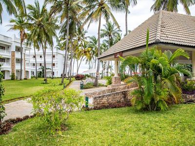 Hotelanlage mit tropischem Garten, Palmen und einem offenen Pavillon nahe dem Strand.