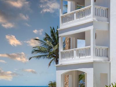 Weißes mehrstöckiges Hotelgebäude mit Balkon neben dem Meer und blauem Himmel.