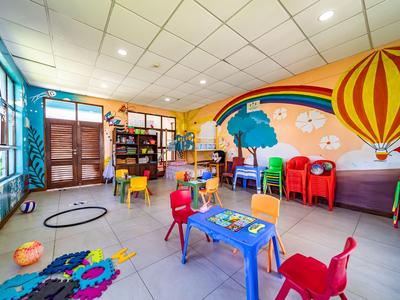 Bunter Spielraum mit Tischen, Stühlen und einer Wandbemalung mit Heißluftballon in einem Hotel.