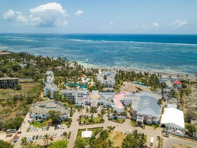 Luftaufnahme eines Resorts mit Schwimmbädern neben einem tropischen Strand und blauem Meer.