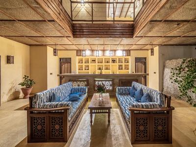 Offener Lounge-Bereich mit zwei blauen Sofas, Holztisch und traditionellem Holzdesign.