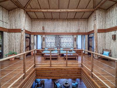 Helles Hotelinterieur mit Holzpaneelen, Sitzbereich und Balustrade mit Metallgeländer.