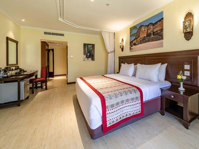 Modernes Hotelzimmer mit großem Bett, Schreibtisch, Stuhl und heller Dekoration.