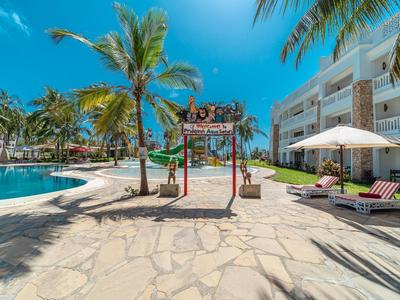 Hotelterrasse mit Swimmingpool, Palmen und Liegestühlen unter klarem blauem Himmel.