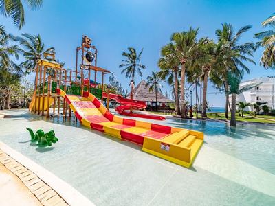 Bunter Wasserspielplatz mit Rutschen und Palmen in einem Hotelpool unter blauem Himmel.