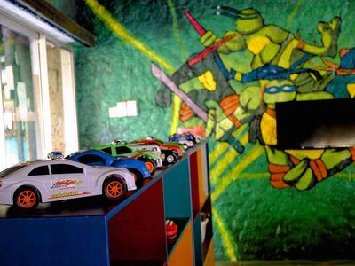 Barevná stěna dětského pokoje s malbou Teenage Mutant Ninja Turtles a hračkami aut na policích.