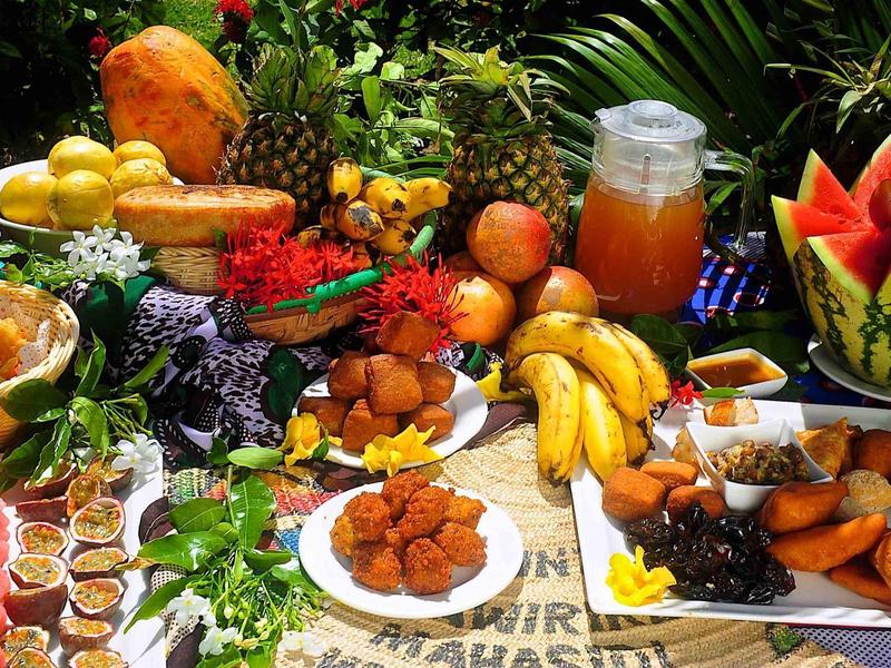 Barevný bufet s čerstvým ovocem, pečivem a nápoji na venkovním stole.