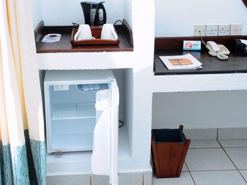 Otevřená malá lednička a stůl v světlém hotelovém pokoji