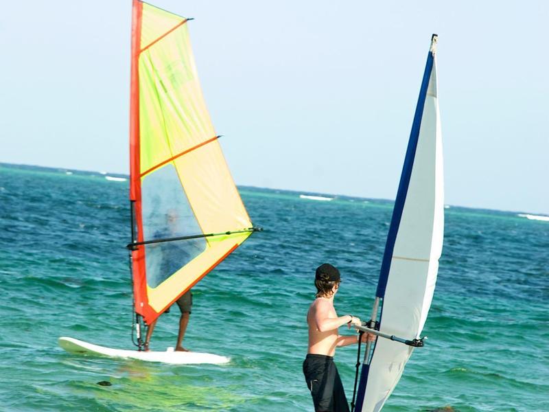 Dva lidé windsurfing na moři za jasné oblohy.