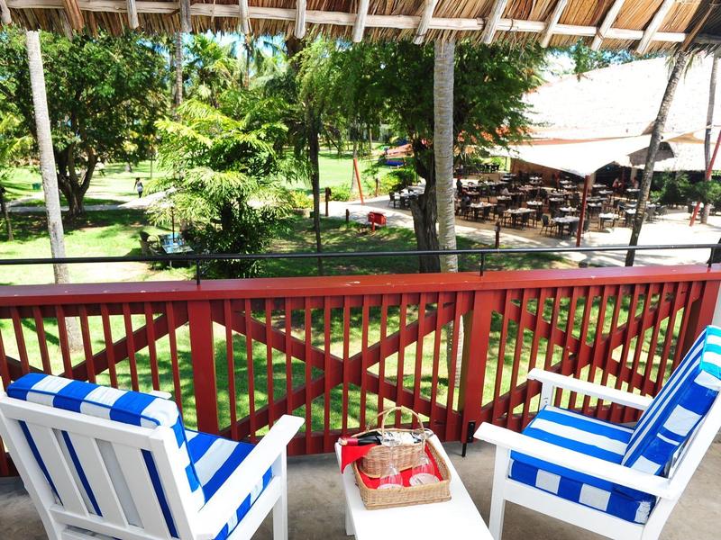 Dvě modrobílé židle s malým stolem na kryté terase s výhledem do zahrady.