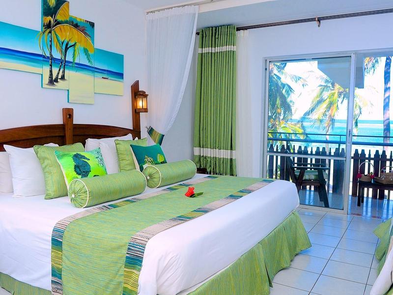 Světle zařízený hotelový pokoj s výhledem na moře a balkonem