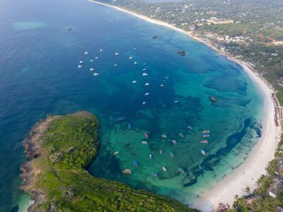 Luchtfoto van een baai met helder water, witte zandstranden en talrijke boten.