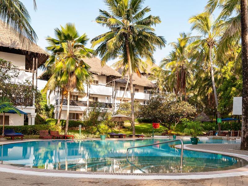 Rond zwembad van het hotel met palmbomen en parasols in tropische omgeving.