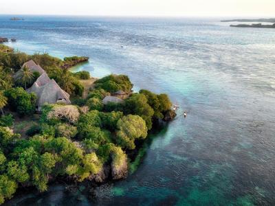 Grüne Küstenlinie mit Bungalows am klaren blaugrünen Meer, ideal für einen ruhigen Urlaub.