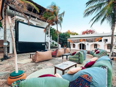 Freiluftkino mit gemütlicher Sitzgelegenheit und Palmen vor klarem blauem Himmel.