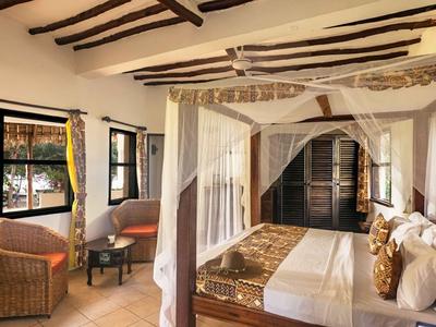 Helles Schlafzimmer mit Baldachinbett und Korbsesseln, rustikale Holzbalken und Fenster.