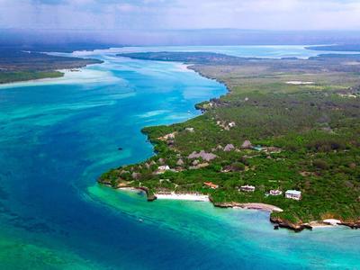 Luftaufnahme einer tropischen Insel mit klarem blauem Wasser, dichtem Grün und Strandhotels.