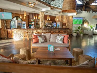Hell eingerichtete Hotel-Lounge mit gemütlichen Sitzbereichen, Holzmöbeln und großen Fenstern.