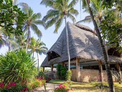 Traditionelles tropisches Bungalowhotel umgeben von Palmen und üppiger Vegetation bei klarem Himmel.