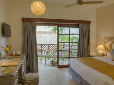 Chambre d'hôtel lumineuse avec balcon, lit double et bureau.