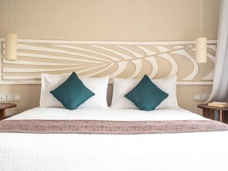 Lit d'hôtel moderne avec linge de lit blanc, trois oreillers et tête de lit élégante.