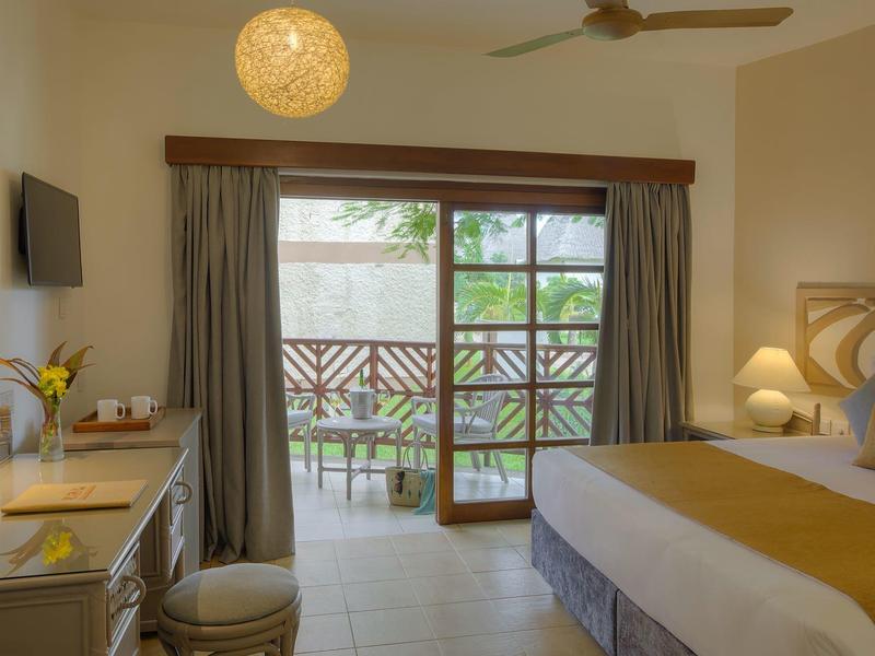 Chambre d'hôtel lumineuse avec balcon, lit double et bureau.