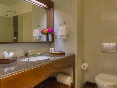 Clean bathroom with sink, mirror, toilet, and fresh towels in a hotel room.