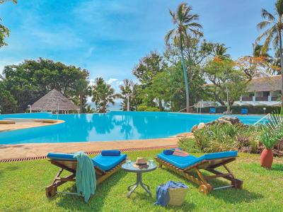 Zwei Liegestühle mit Handtüchern und Getränken am Pool in tropischer Gartenanlage.
