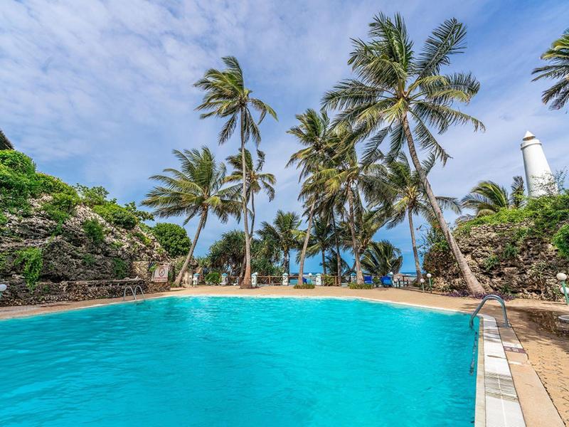 Blue pool with palm trees and sky at tropical resort