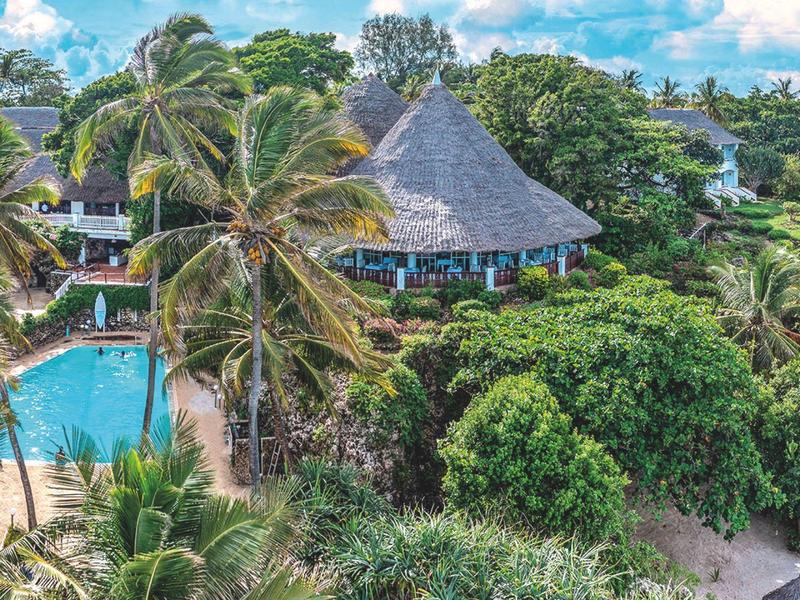 Tropical resort with swimming pool, palm trees, and thatched pavilion under a blue sky.
