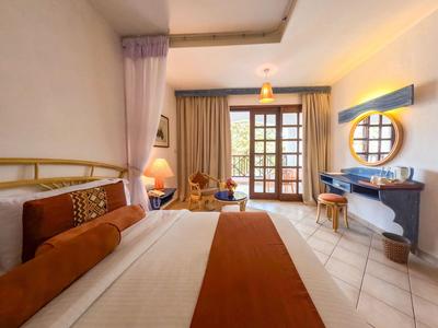 Gemütliches Hotelzimmer mit großem Bett, Sitzbereich und Balkon mit viel natürlichem Licht.